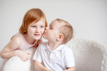 The blond boy kisses the redhead girl on the cheek