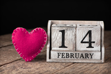Wooden calendar show of February 14. Pink heart.