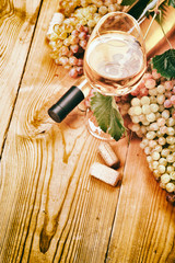 A glass of white wine and grapes on a wooden table