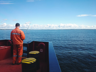 Seaman fishing from the cargo vessel.