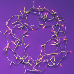 Creative Christmas lights frame decoration with purple background. Minimal flat lay concept.