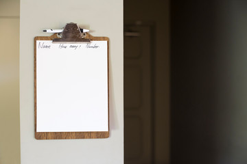 White message board hanging on white wall. wooden clipboard