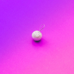 Creative Christmas shiny silver ball decoration on purple and pink gradient holographic background. Minimal flat lay concept.