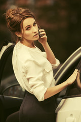 Young fashion business woman calling on cell phone outside a her car