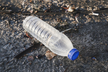 Spilled seaport garbage by the sea of a big city. Empty used dirty plastic bottles. Large amount urban rubbish. Dirty pier city port. Environmental pollution. Ecological problem. Bokeh city buildings