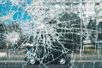 Criminal incident at the bus stop. Shooting a pistol. Hole and cracks in the glass of a city bus stop. Cracked glass texture against the blue sky. Cracked glass with a hole from a bullet. Vandalism