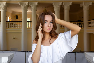 Fototapeta na wymiar Beautiful girl in white dress. leaned on the railings.