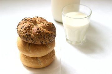 Wheat and rye Kaiser buns with flax and sesame seeds served with milk, healthy breakfast.