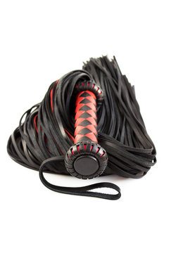 Red-black floger with a patterned handle and leather tails. vertical photo on white background.concept of pleasure from pain