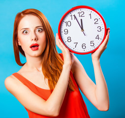 Redhead girl with huge clock on blue background.