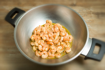 shrimp in wok pan on wooden background