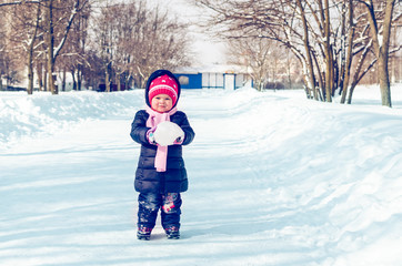 Fototapeta na wymiar Little girl walks in winter on a snowy alley