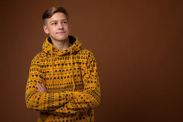 Fototapeta premium Studio shot of young handsome teenage boy against brown backgrou