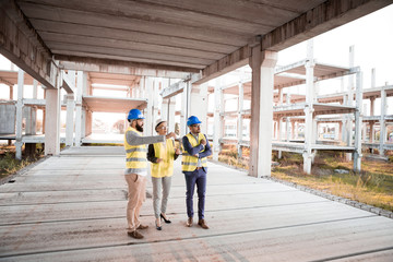 Architects and civil engineers are located at an old abandoned construction site where construction will begin again.