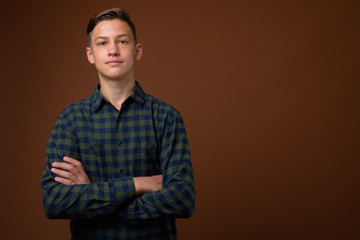 Obraz premium Studio shot of young handsome teenage boy against brown backgrou