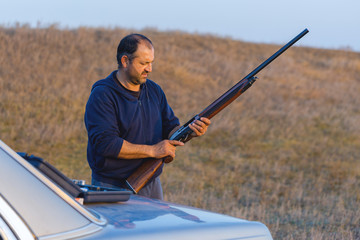 The guy shoots cartridges with a gun in nature, The hunter shoots at the target at sunset