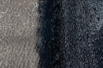 Freshly laid black bitumen asphalt with a high edge to the gravel showing the structure. Laying a new asphalt on the roads. Construction of the road.