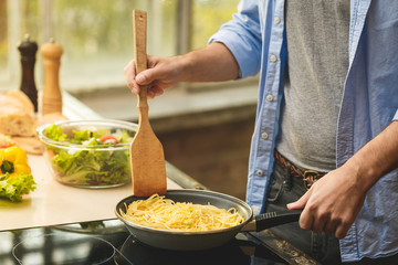 Portrait of young man preparing delicious and healthy food in the home kitchen on a sunny day. Close-up.