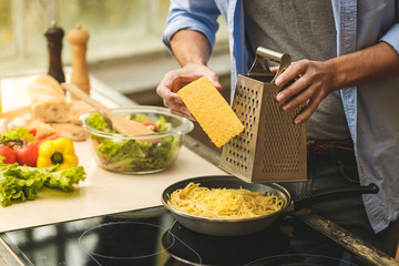 Portrait of young man preparing delicious and healthy food in the home kitchen on a sunny day....