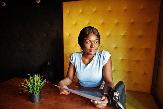 African American Girl Sitting At Cafe With Menu At Hands. Black Woman Having Rest.