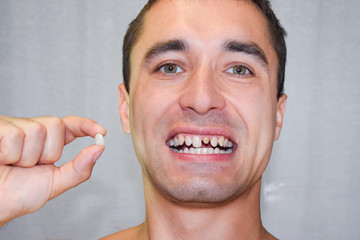 Dental prosthesis of metal ceramics in the hand of a man without a tooth. A patient without a tooth...