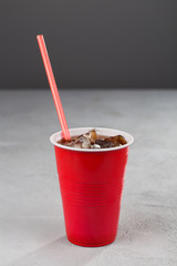 red Cup with soda and red straws on grey background