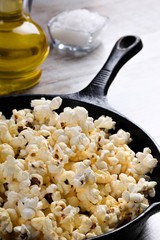  Prepared popcorn in frying pan, corn seeds in bowl and corncobs on kitchen table.Air salty popcorn. Salt popcorn on the wooden background . Chees .Popcorn texture