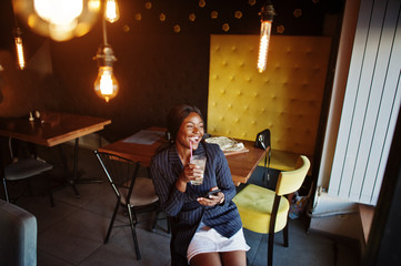 African american businesswoman drinking cocktail lemonade in cafe. Black girl having rest with mobile phone.