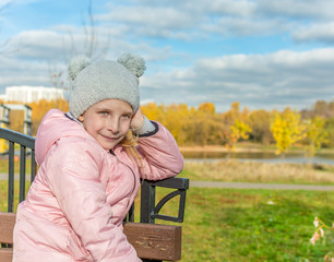 Mellow autumn. Portrait of the nice little girl on a bench. Copy space for text.