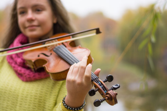 Violin in the foreground, girl playing the violin in the autumn park.