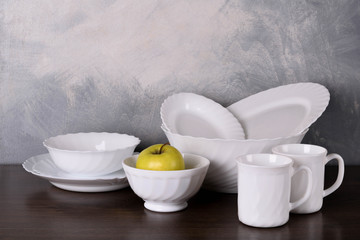  White dishware stacked on a wooden table against grey background on wooden table