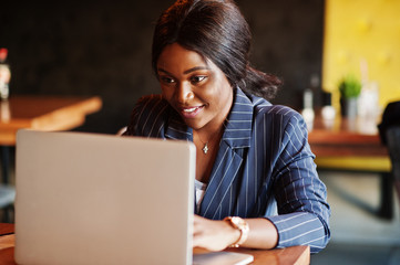 African american businesswoman sitting at table in cafe. Black girl working with laptop.