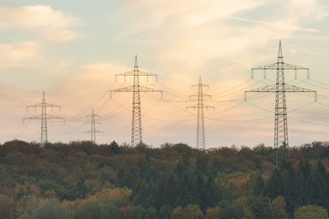 Power poles over autumn forest sunset