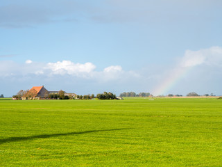 Polder landscape with pasture, farmhouse and rainbow near Workum, Friesland, Netherlands