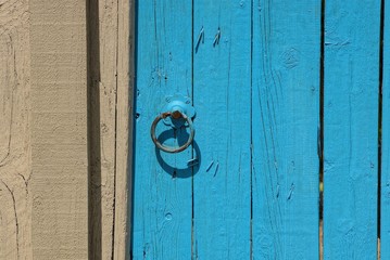door knob on the boards of a blue wooden door and a gray fence