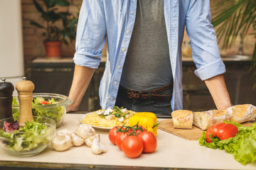 Man preparing delicious and healthy food in the home kitchen on a sunny day. Close-up.