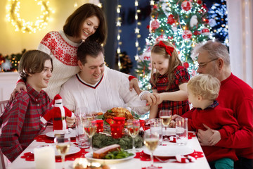 Family with kids having Christmas dinner at tree