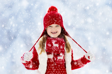 Naklejka na ściany i meble Child playing in snow on Christmas. Kids in winter