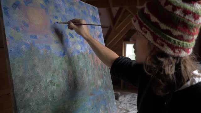 Man artist paints a picture of oil paints in the attic. 4K