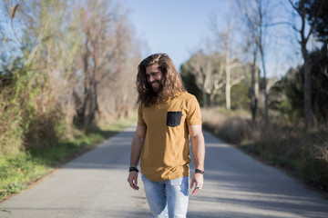 young man with long hair posing in the middle of a path