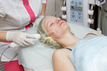 Woman getting facial darsonval therapy at cosmetology clinic