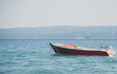 Fototapeta premium Lonely red boat moored in the open sea.