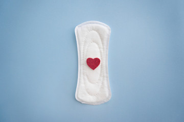Menstrual pad with red heart on color background
