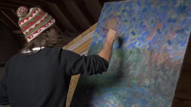 Man artist paints a picture of oil paints in the attic. 4K