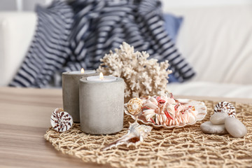Fototapeta na wymiar Burning candles and seashells on wooden table