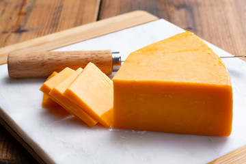 Piece of bright yellow hard cheese cheddar, originating in the English village of Cheddar in Somerset