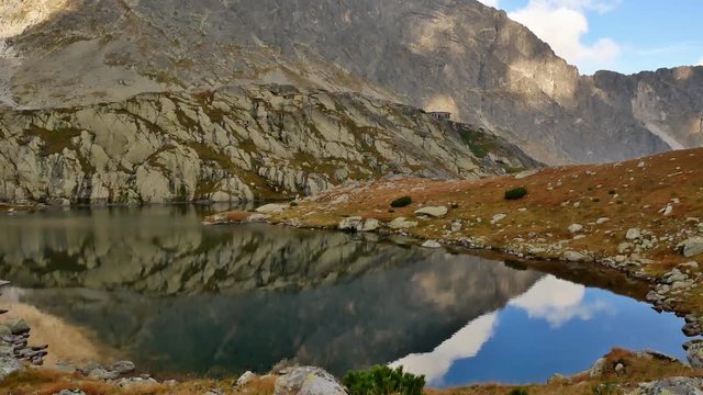 Pan over mountain tarn reflecting the sky upwards to mountain peak (Lomnitzky stit, high tatras, slovakia)