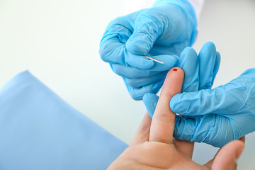 Doctor using lancet to get blood sample for test, closeup