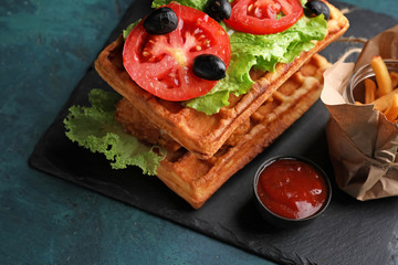 Delicious waffles with chicken and vegetables on slate plate