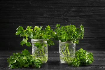 Jars with fresh aromatic parsley on dark wooden table